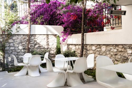a restaurant with white chairs and purple flowers at City Loft Hotel in Patra
