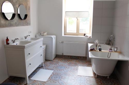 een witte badkamer met een bad, een wastafel en een bad bij Apartamenti Nr. 33 in Talsi