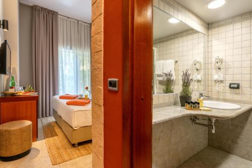 a bathroom with a tub and a sink and a bed at Hotel Podstine in Hvar