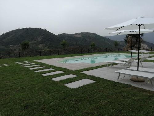 a swimming pool with tables and an umbrella at Mama Lina in Patti