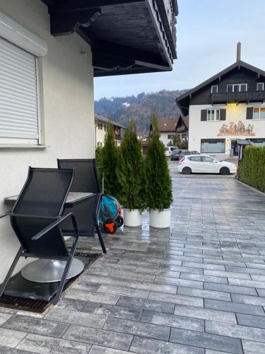 a patio with a black chair and potted plants at Ferienhaus Butterfly in Garmisch-Partenkirchen