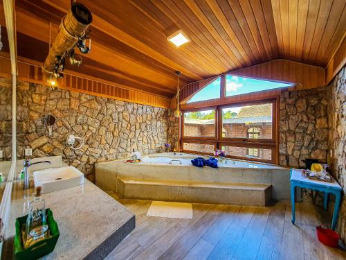 a large bathroom with a large tub and a stone wall at Verde que te quero Ver-te - Chalés in Visconde De Maua