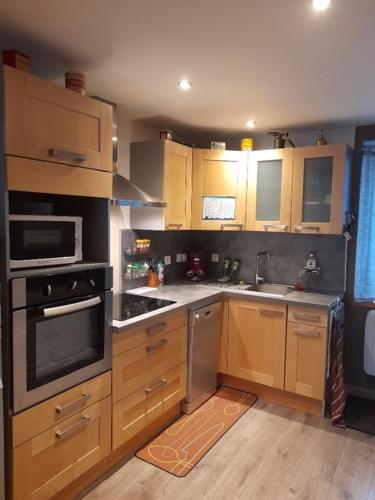 a kitchen with wooden cabinets and stainless steel appliances at Le saquet in Ax-les-Thermes