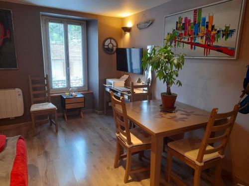 a living room with a table and a desk with a plant at Le saquet in Ax-les-Thermes