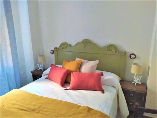 a bedroom with a bed with red and orange pillows at Casa Rural del Tío Maino in Becerril de la Sierra