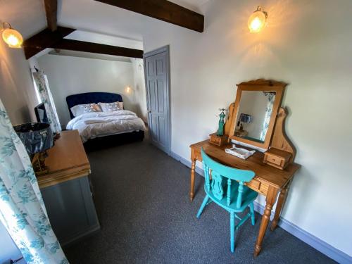 1 dormitorio con escritorio, espejo y cama en Inglenook Cottage near Porthcawl and Beaches en North Cornelly