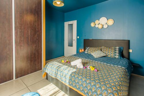 Un dormitorio azul con una cama con flores. en Le Dashan Cosy-Rénové-Proche étang et Plage en Saint-Paul