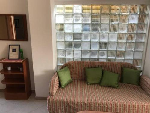 - un canapé avec des oreillers verts devant une fenêtre dans l'établissement App Anita, à Premantura