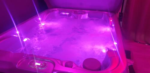 a hot tub with pink lights in a room at Paradis Secret Spa in Damprichard