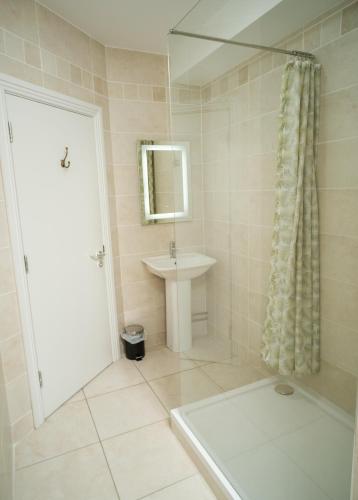 Un baño blanco con lavabo y ducha. en The Lodge Doolin, en Doolin