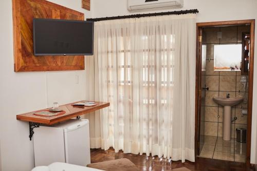 a living room with a television and a curtain at Pousada Casarão in Jaraguá do Sul