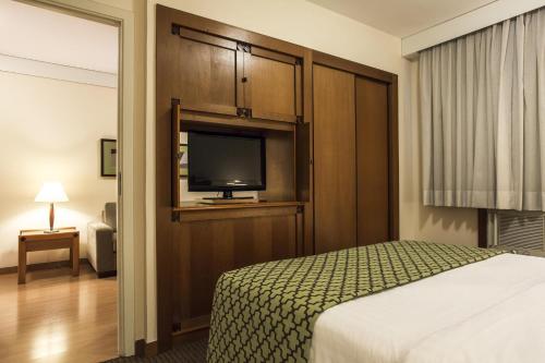a hotel room with a bed and a flat screen tv at Estanplaza Nações Unidas in Sao Paulo