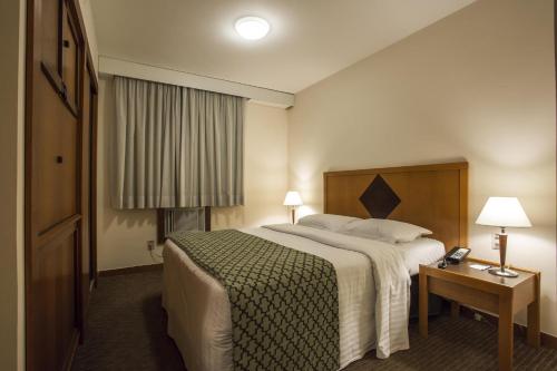 a hotel room with a large bed and a telephone at Estanplaza Nações Unidas in Sao Paulo