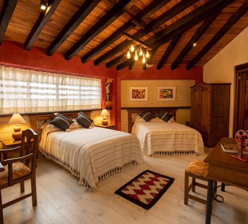two beds in a room with red walls and wooden ceilings at La Casona Colorada San Felipe del Agua in Oaxaca City