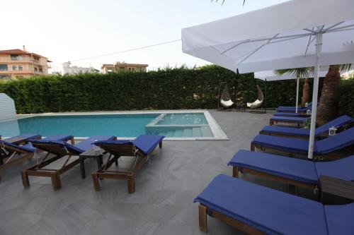 un grupo de sillas azules y una sombrilla junto a la piscina en Heksamil Hotel, en Ksamil