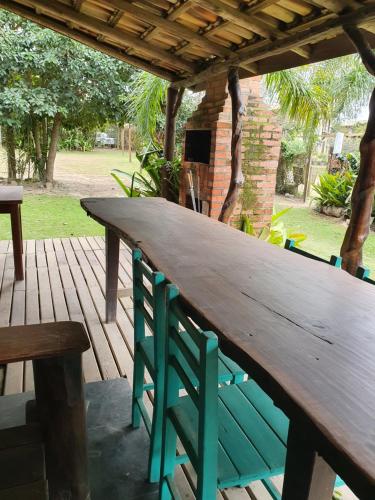 a large wooden table on a deck with a bench at Morada Amazona in Praia do Rosa