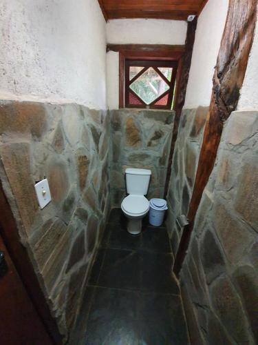 a small bathroom with a toilet in a stone wall at Morada Amazona in Praia do Rosa