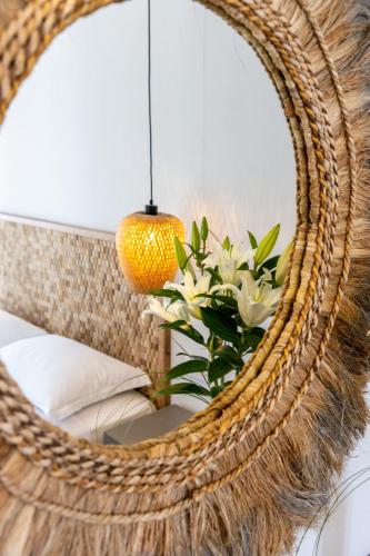 a wicker chair with a mirror and a vase of flowers at Sea & Sun Paros in Naousa