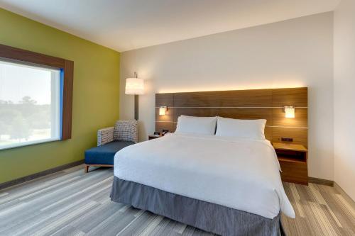a hotel room with a large bed and a chair at Holiday Inn Express - Wilmington - Porters Neck by IHG in Wilmington