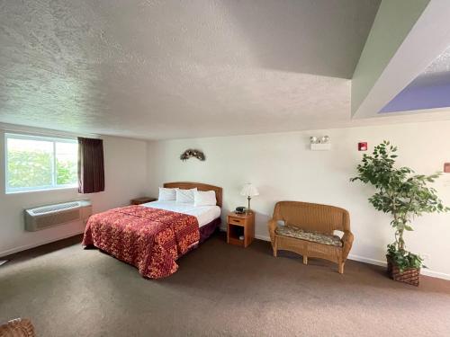 une chambre d'hôtel avec un lit et une chaise dans l'établissement VIBE INN - WHIRLPOOLS SUITES - Lyons, à Lyons