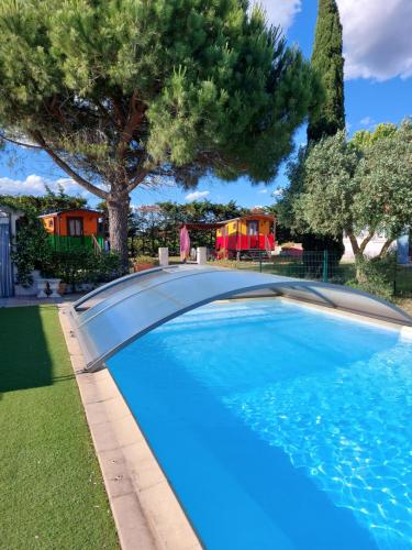 - une piscine dans une cour avec des arbres et des maisons dans l'établissement Gites et Roulottes Du Grand Puits, à Saint-Laurent-dʼAigouze