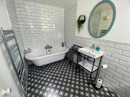 y baño con bañera, lavabo y espejo. en Inglenook Cottage near Porthcawl and Beaches, en North Cornelly