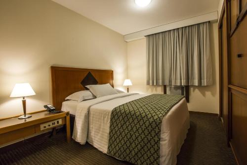 a hotel room with a bed and a table and lamp at Estanplaza Nações Unidas in Sao Paulo