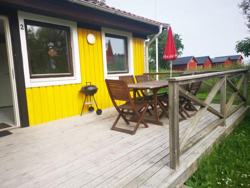 a house with a table and chairs on a deck at Susanne's stugor Böda hamn in Böda