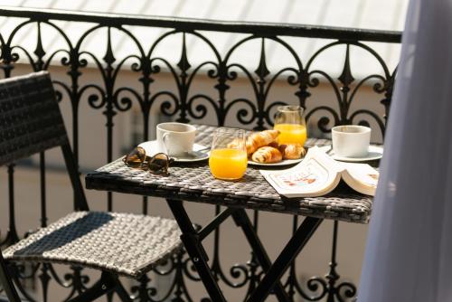 a table with a breakfast of orange juice and croissants at Hôtel Le Milie Rose in Paris