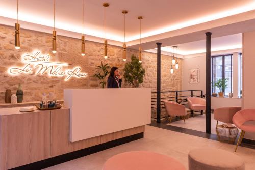 a woman standing at the counter of a restaurant with a white reception desk at Hôtel Le Milie Rose in Paris