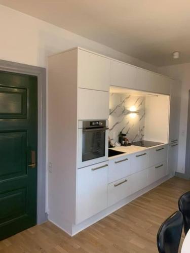 a kitchen with white cabinets and a microwave at Ferie lejlighed i Skagen -huset med den grønne dør in Skagen