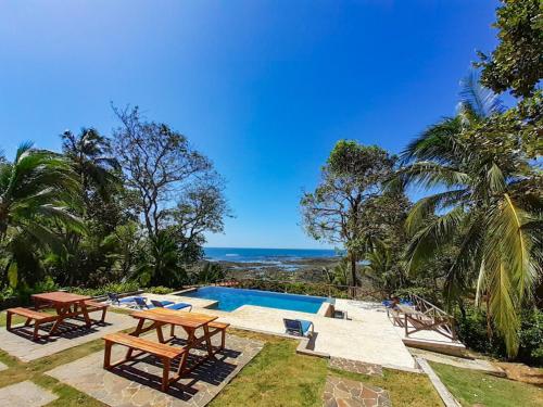 a pool with picnic tables and the ocean in the background at Hotel Santa Catalina Panamá in Santa Catalina