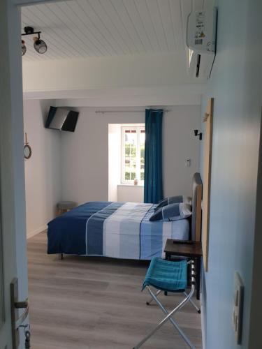 een slaapkamer met een bed, een stoel en een raam bij Chambres de Villée in Saint-Georges-de-Gréhaigne