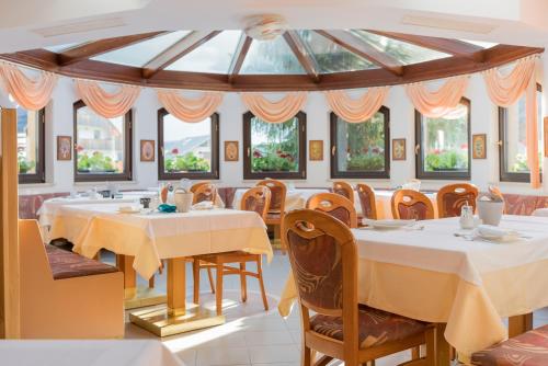 a dining room with tables and chairs and windows at Garni Hotel Miklič in Kranjska Gora