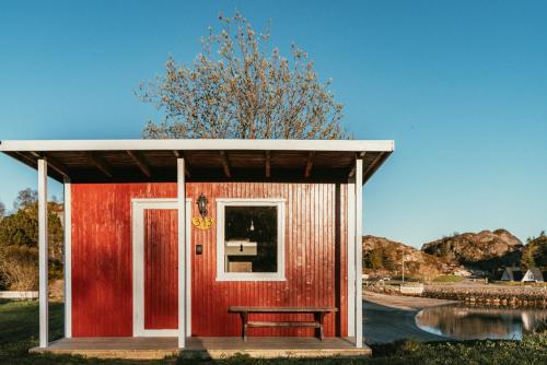 a red shed with a bench in front of it at Skårungen - Hotel, Cabins and Camping in Kabelvåg