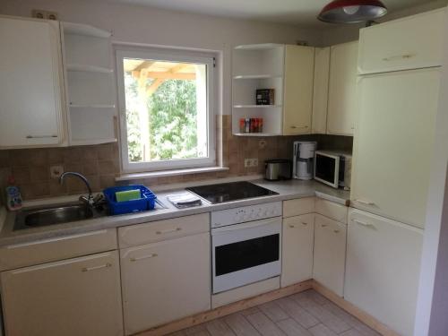 eine Küche mit weißen Schränken, einem Waschbecken und einem Fenster in der Unterkunft Pochebachhäusl in Kurort Jonsdorf