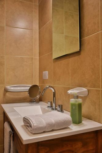 a bathroom with a sink with towels and a mirror at Aguila Mora Aparts in El Chalten