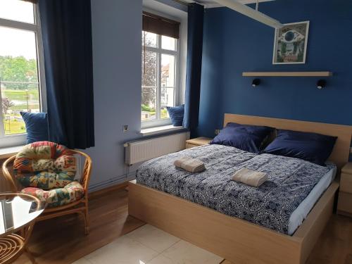a bedroom with a bed and a chair and windows at Warszawska Centrum - w cenie 4 rowery, łódka wiosłowa, kajak, rower wodny, plaża in Mrągowo