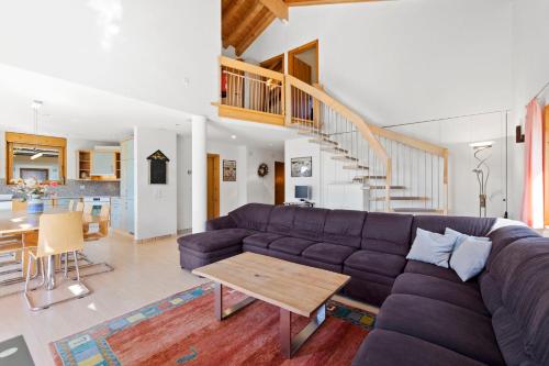 a living room with a purple couch and a table at Golden Peaks Ferienhaus Valbella-Lenzerheide in Valbella