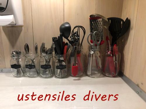 a group of utensils in glass jars on a counter at Appartement champêtre in Saguenay