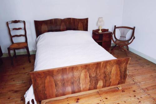 Cama de madera en habitación con 2 sillas en Maison de location saisonnière en Périgord Vert, en Saint-Front-la-Rivière