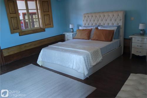 a bedroom with a large bed with blue walls at Quinta da Urtigueira in Felgueiras
