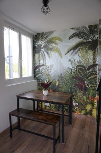 a table in a room with a plant on a wall at Appart Cosy 4 personnes avec terrasse in La Roche-sur-Yon