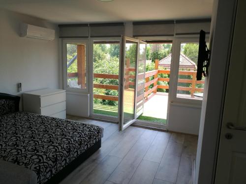 ボニャルツバシュにあるJudit Apartmanのベッドルーム1室(ベッド1台付)、ガラスのスライドドアが備わります。