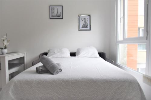 a white bedroom with a bed with towels on it at Studio Dreams Paris in Montévrain