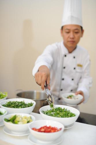 a chef preparing food in bowls on a table at Muong Thanh Holiday Quang Binh Hotel in Dong Hoi