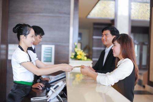 a woman shakes the hand of a man at a counter at Muong Thanh Holiday Quang Binh Hotel in Dong Hoi