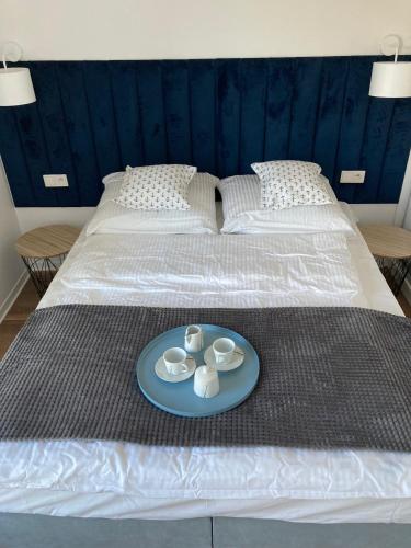a bed with a tray with two cups and a plate on it at Dwa Morza domki całoroczne z ogrodem in Puck