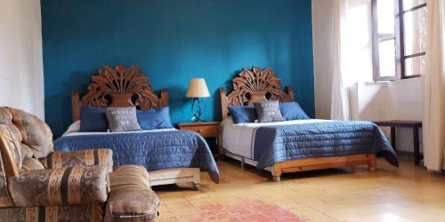 a blue room with two beds and a couch at Hotel Sautto in San Miguel de Allende