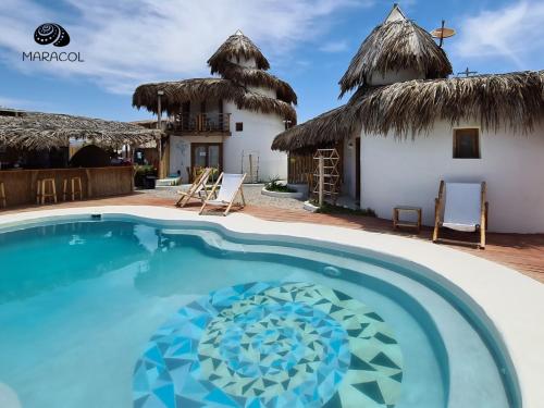 a villa with a swimming pool in front of a house at Maracol Bungalows Vichayito in Vichayito